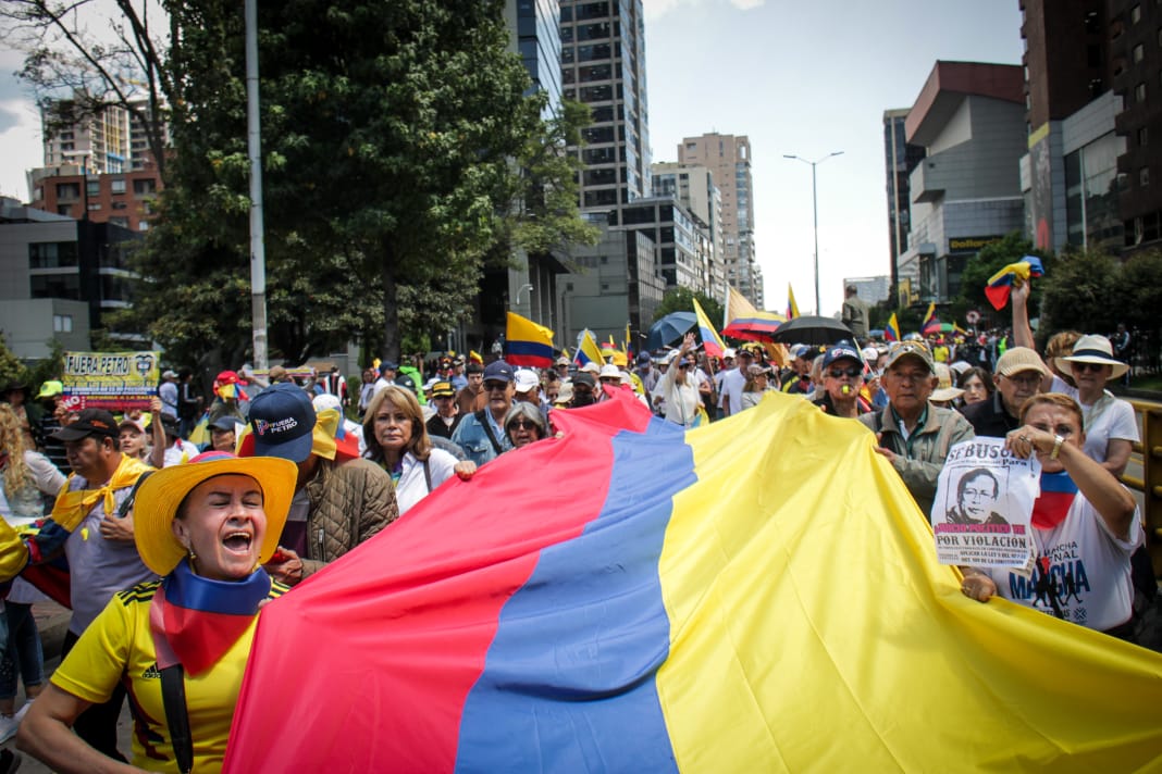 Manifestantes de camino a la plaza de Bolívar con bandera de Colombia 